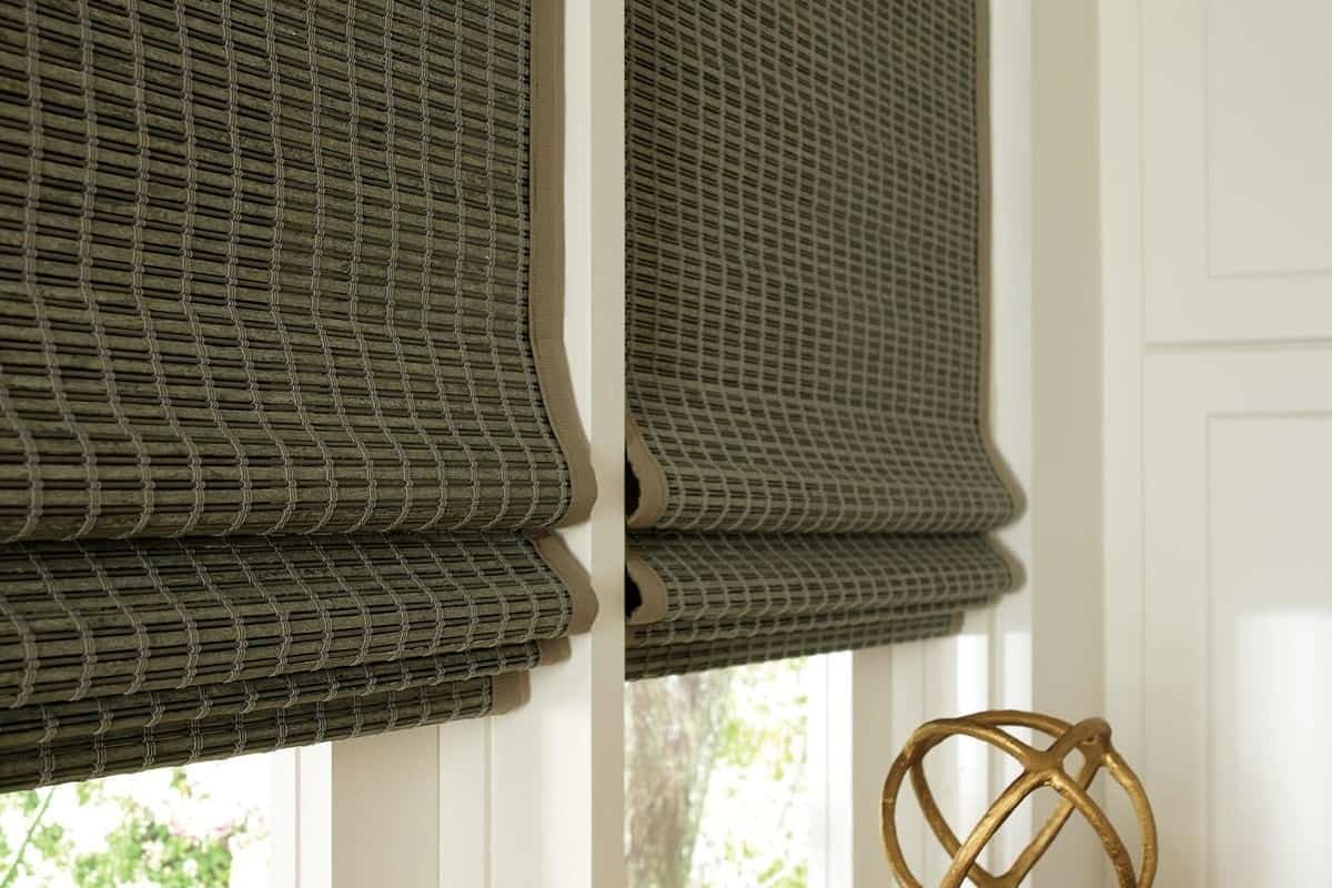 A close up image of brown Hunter Douglas Provenance® Woven Wood Shades hanging in a window